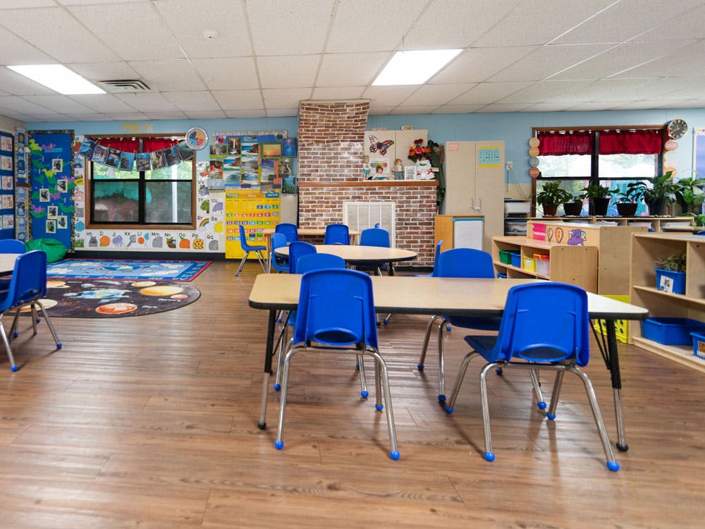 Classroom with small tables and blue chairs, educational decorations on walls