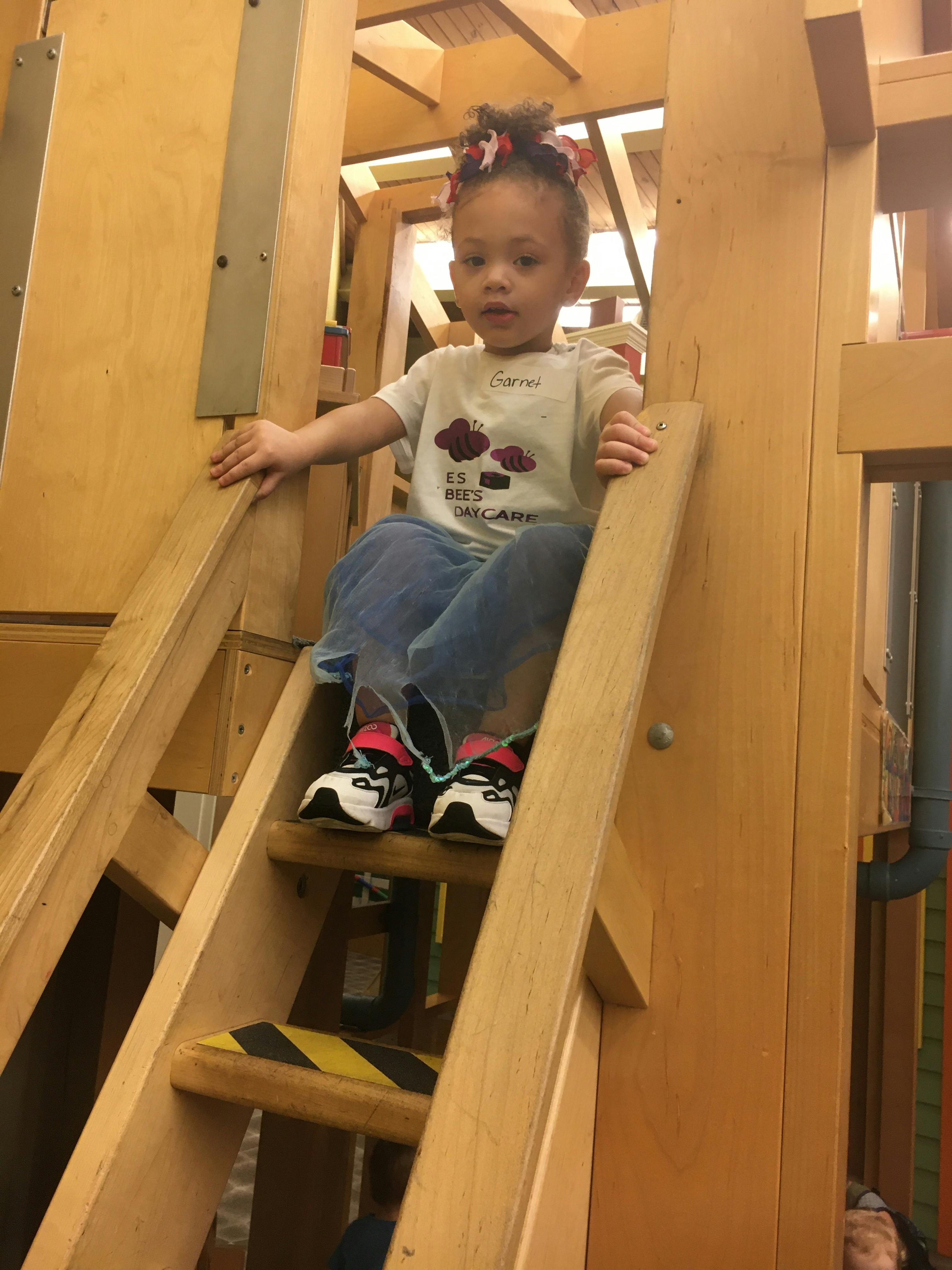 Child sitting on a wooden ladder