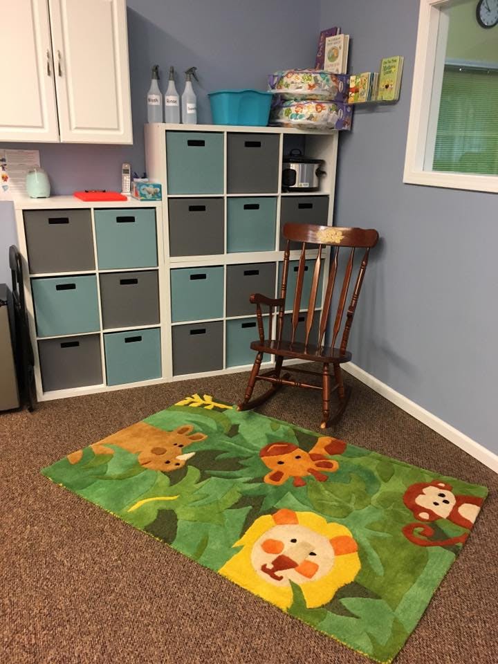 A green rug with cartoon jungle animals on a brown carpeted floor