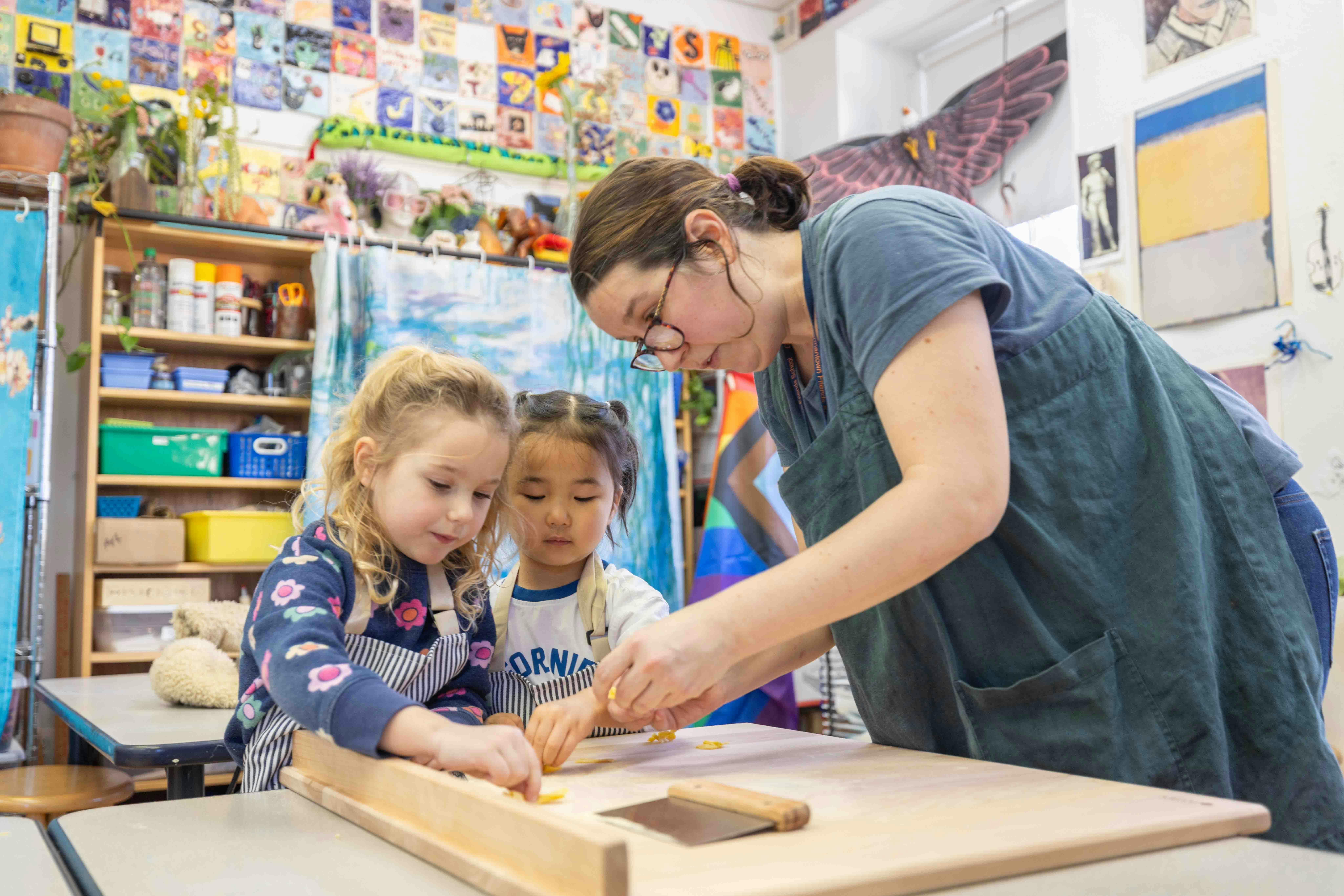 Adult and two children making pasta at a table