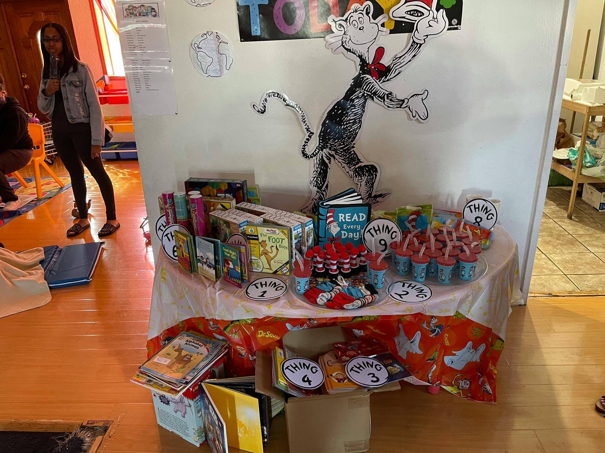 Table with Dr. Seuss decorations and books, person standing in background