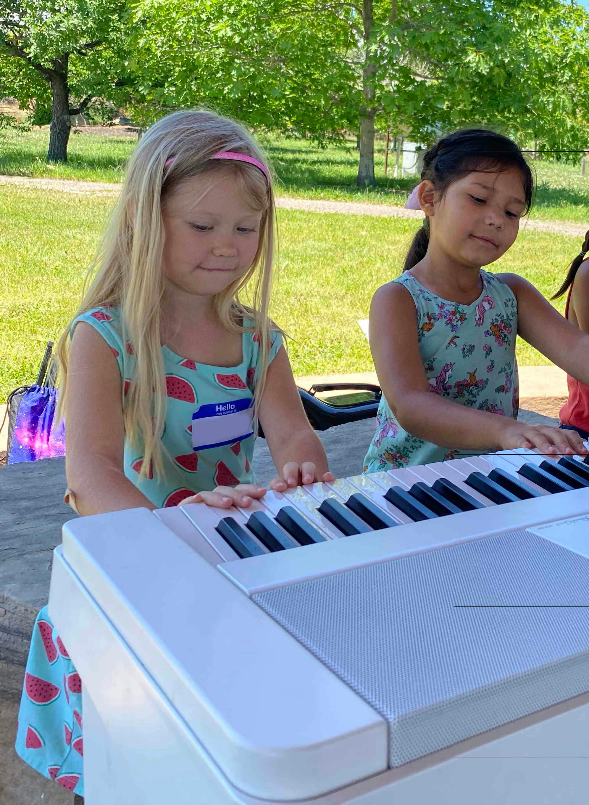Two children playing a keyboard outdoors