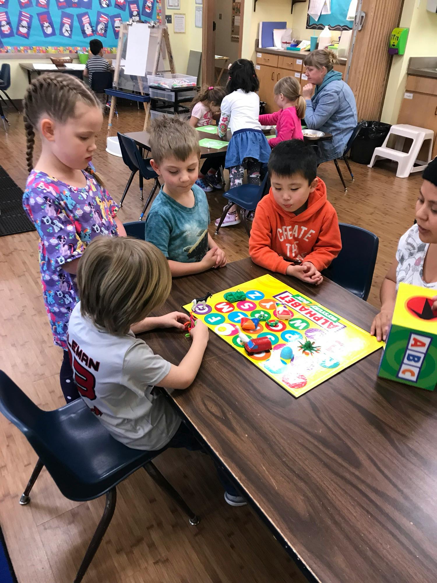 Children playing a board game at a table in a classroom