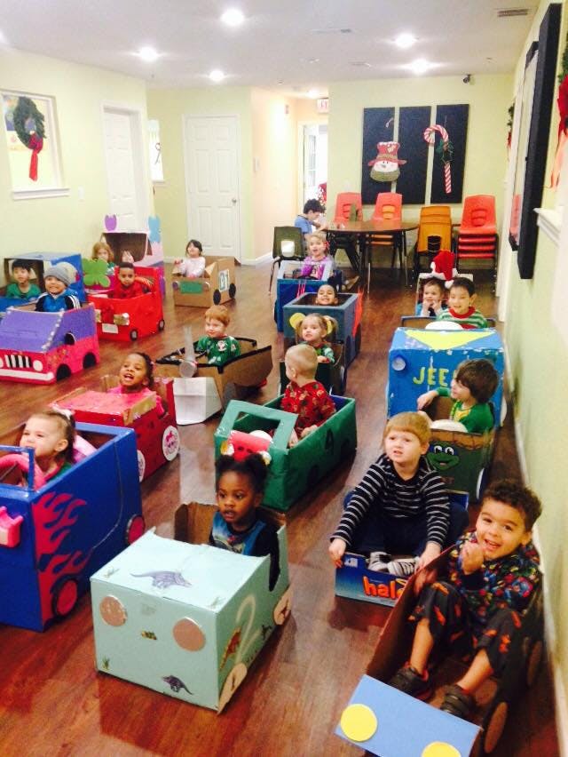 Children sitting in cardboard box cars in a room