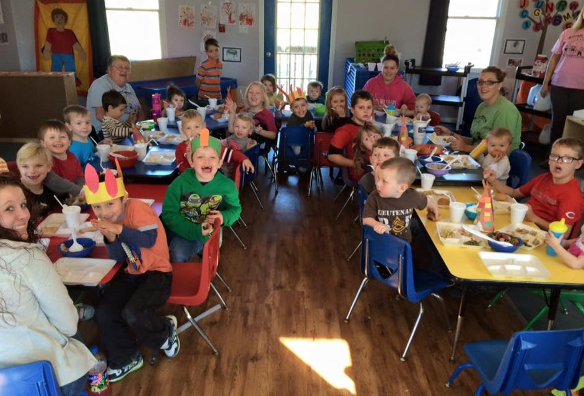 Adults and children sitting at tables in a classroom