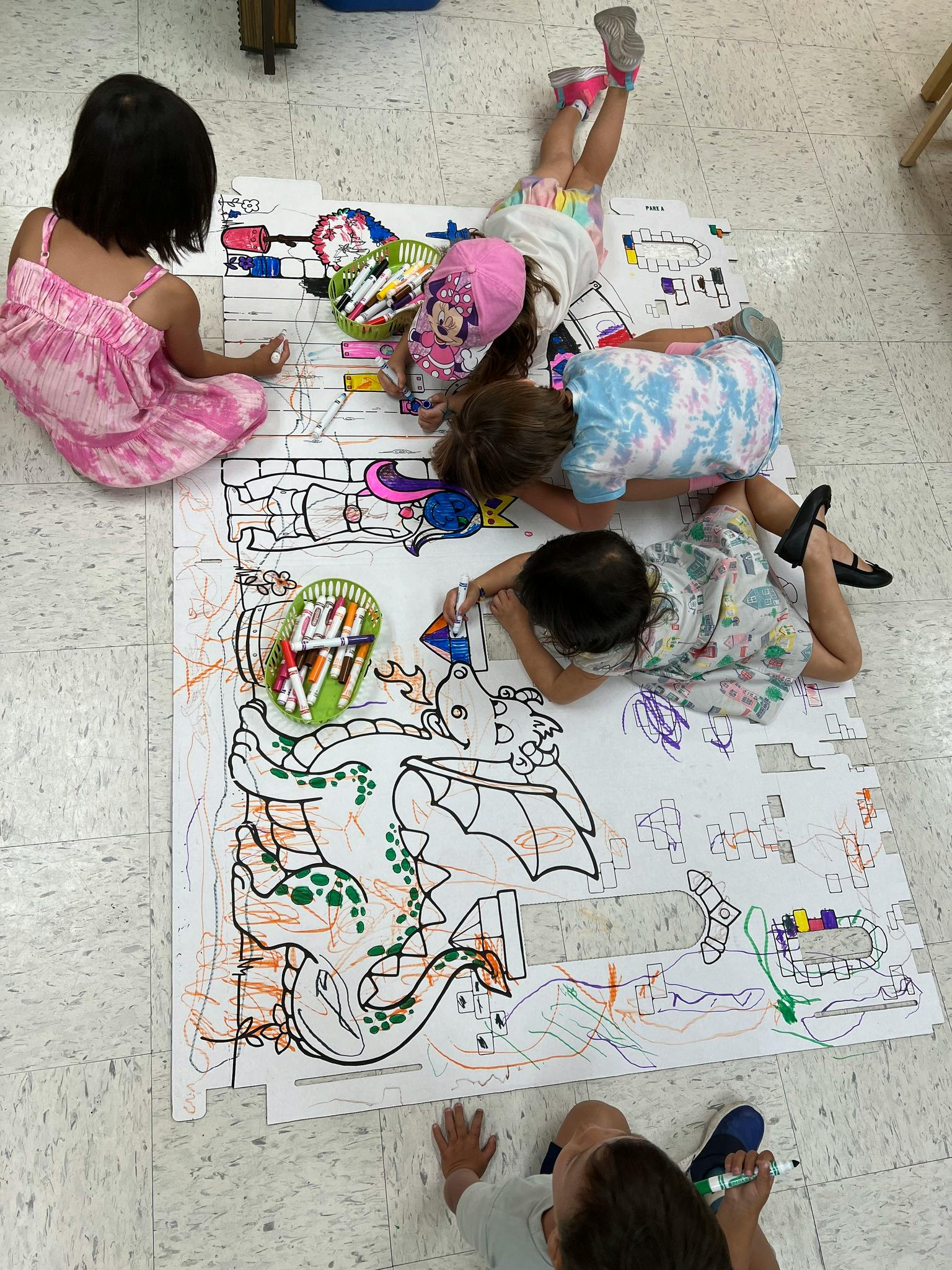 Children coloring a large drawing on the floor