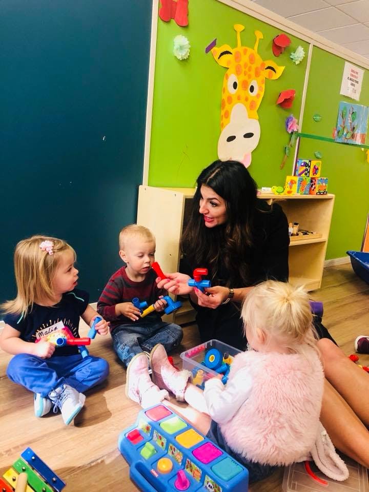 Adult and three children playing with toys on the floor