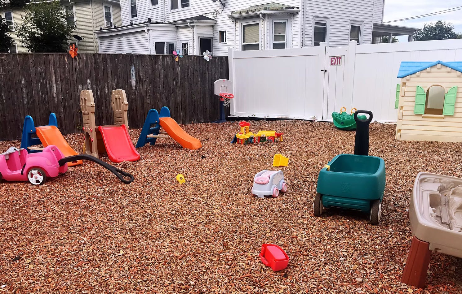Outdoor playground with slides, wagons, and playhouses on wood chips