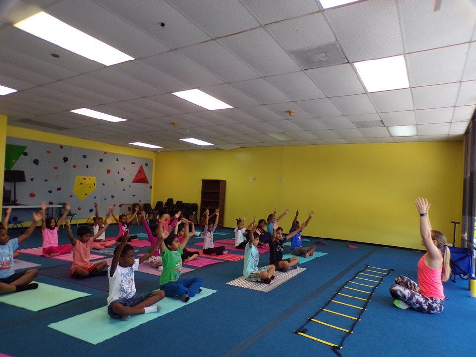 Children and an adult doing yoga in a classroom