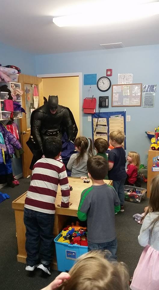 Person in a Batman costume interacting with children in a classroom
