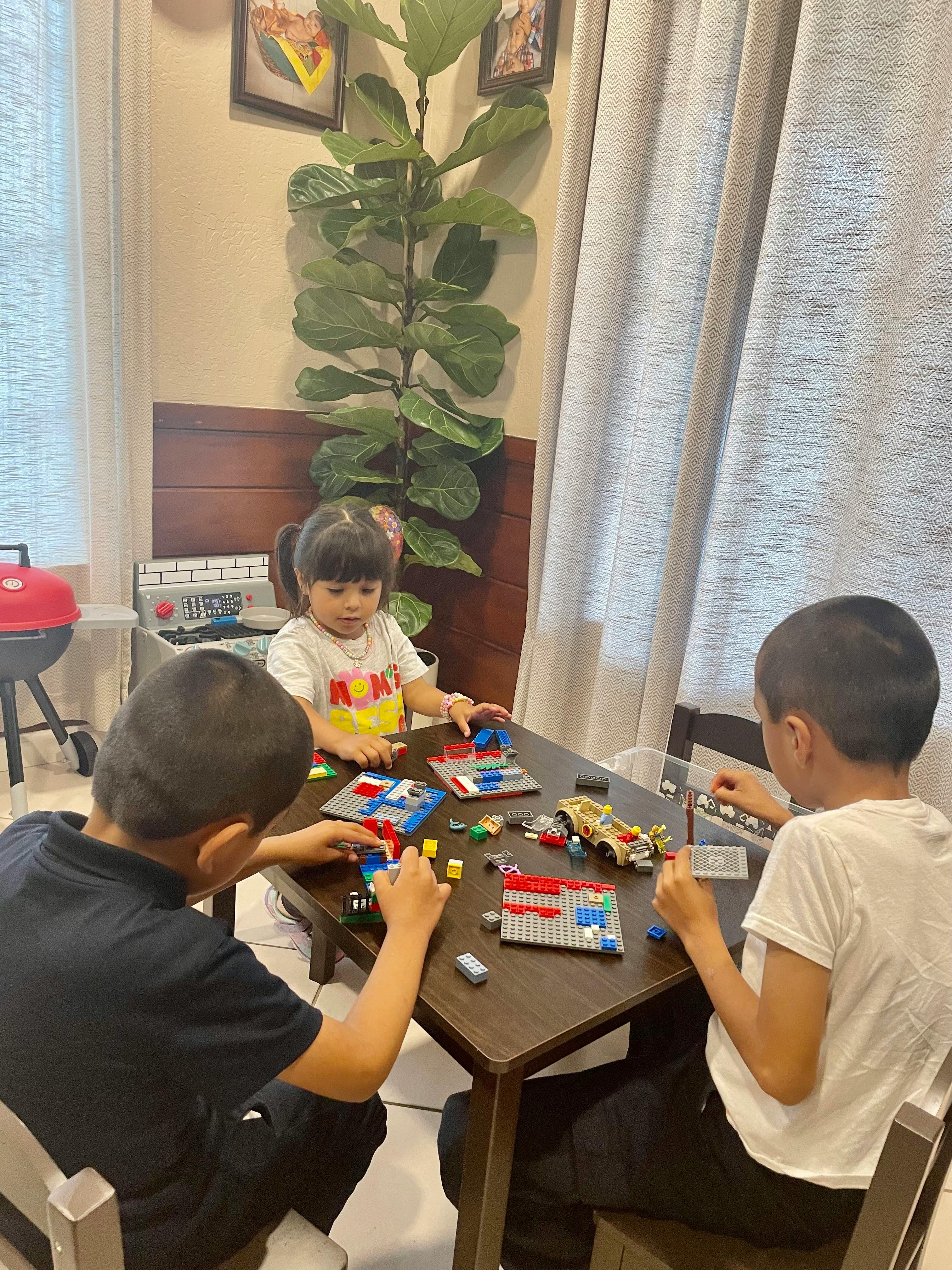 Three children playing with building blocks at a table