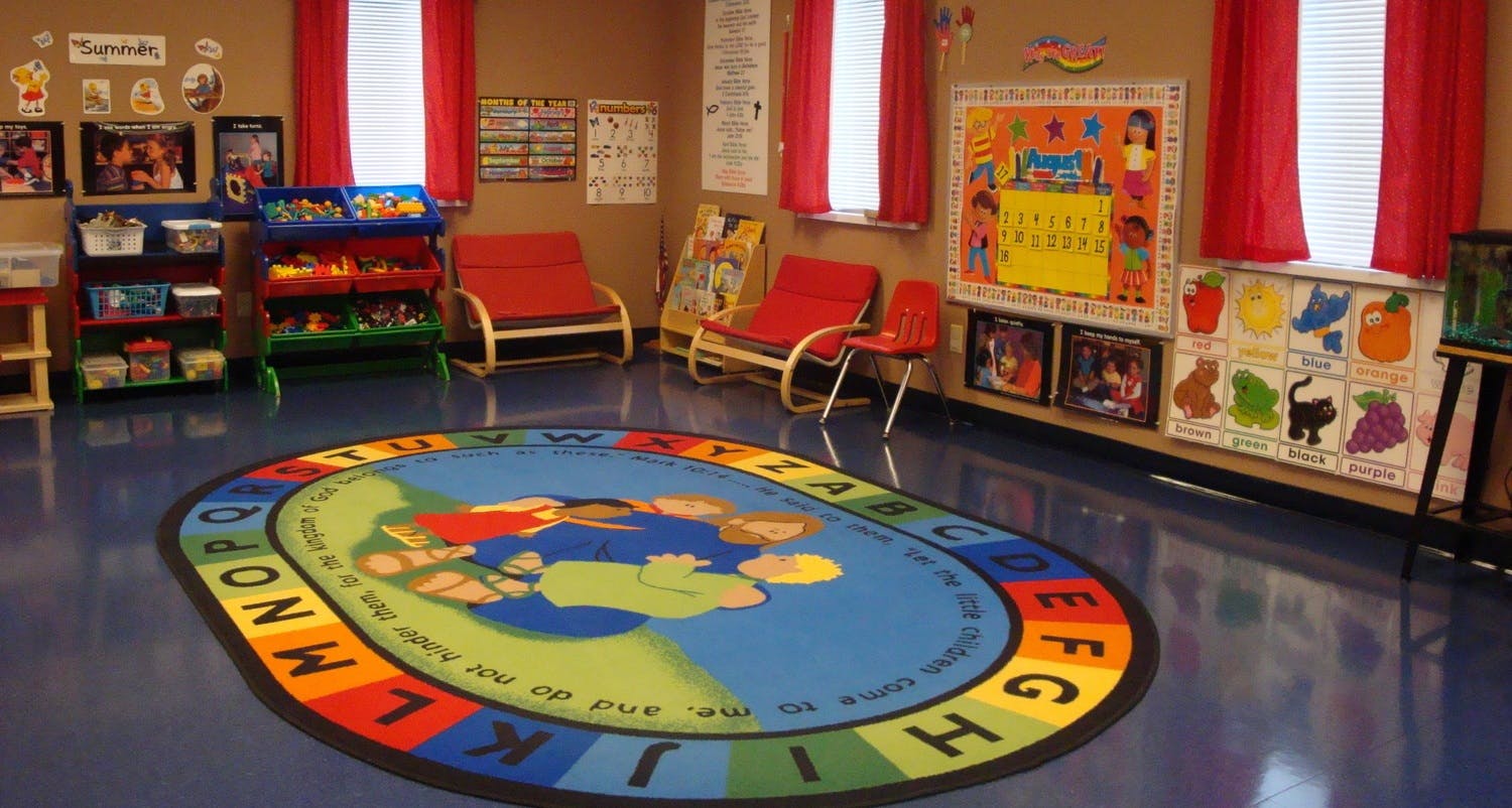Classroom with an alphabet rug, red chairs, and educational posters