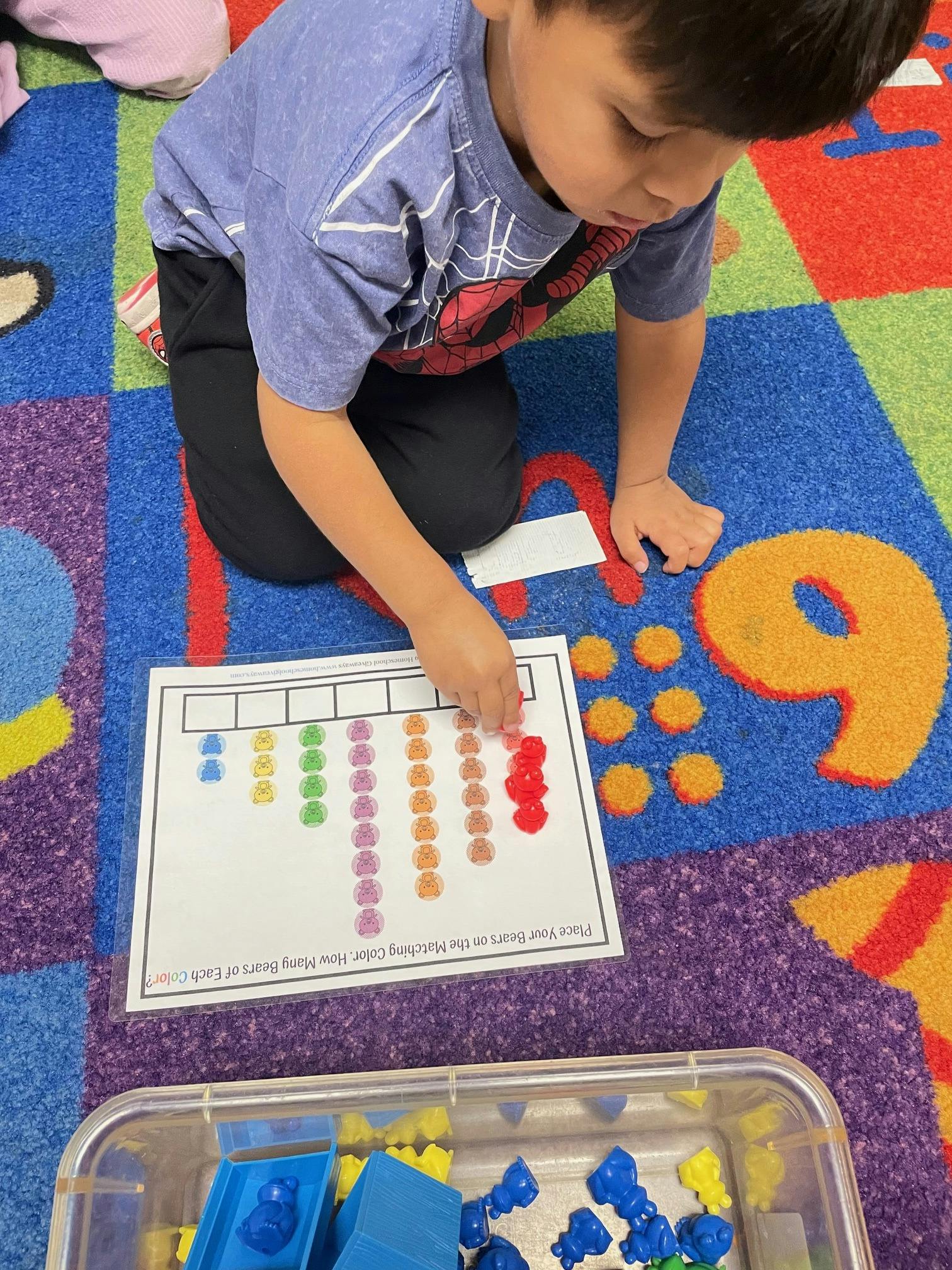Child on a colorful rug placing small objects on a learning mat