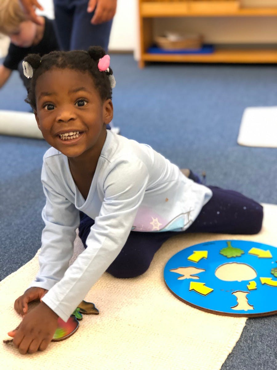 Child kneeling on a mat, playing with a puzzle