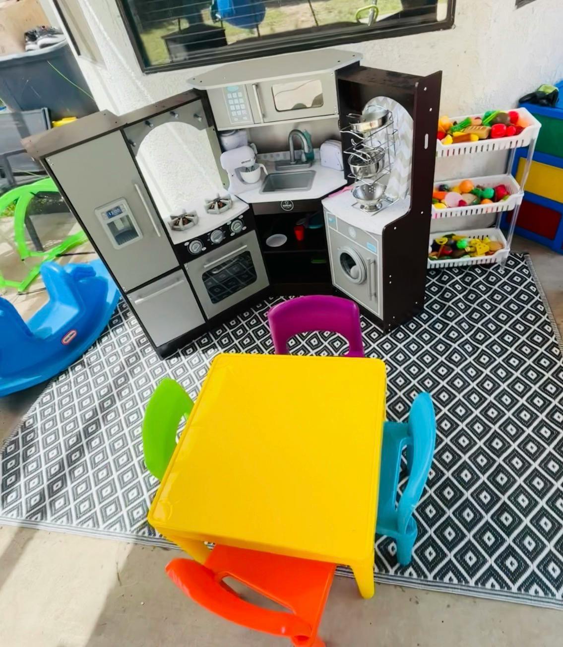 Child's play kitchen set, toy storage bins, and small table with chairs