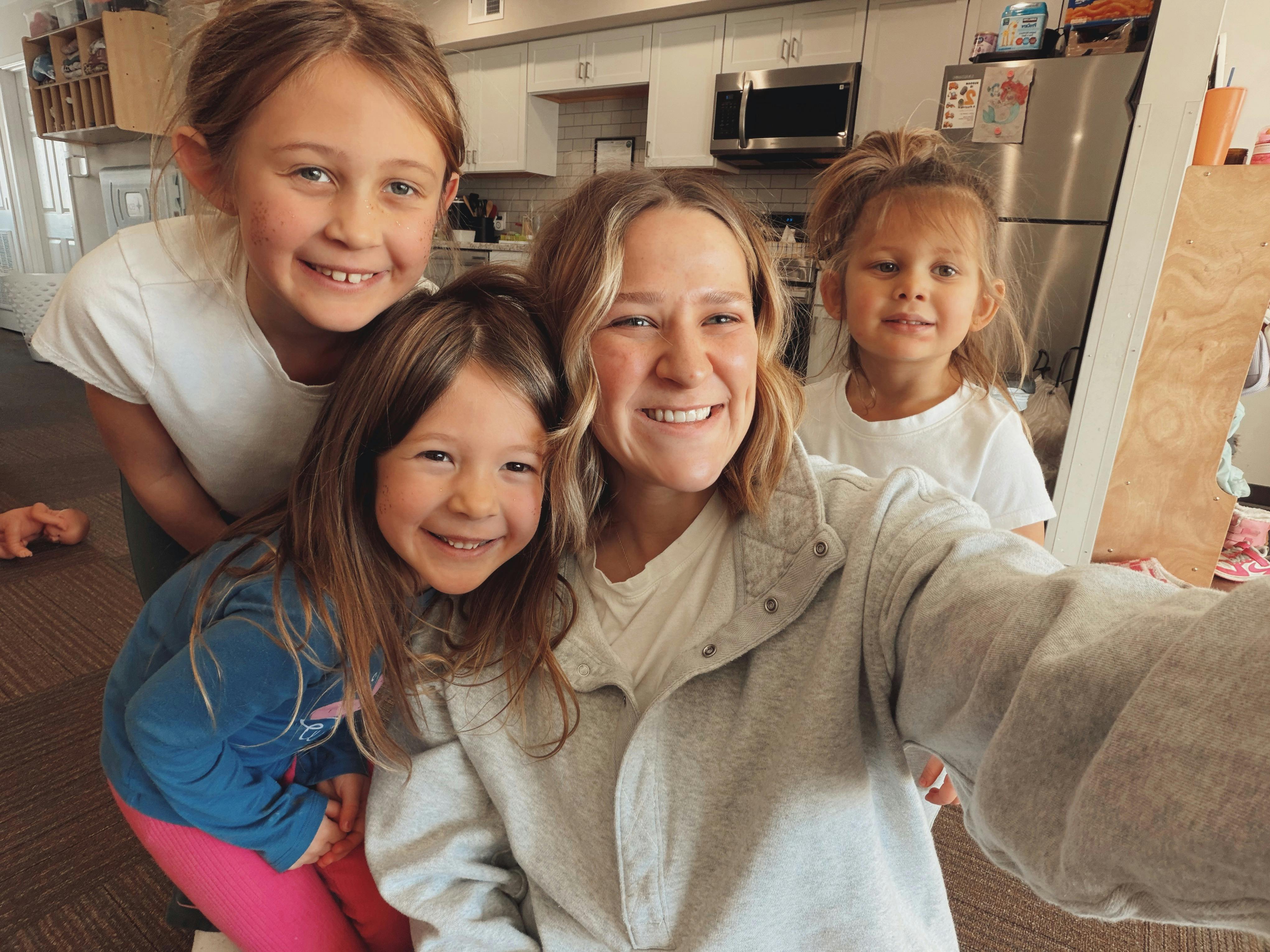 Smiling person taking a selfie with three children