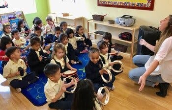 Adult leading a group of children playing musical instruments in a classroom