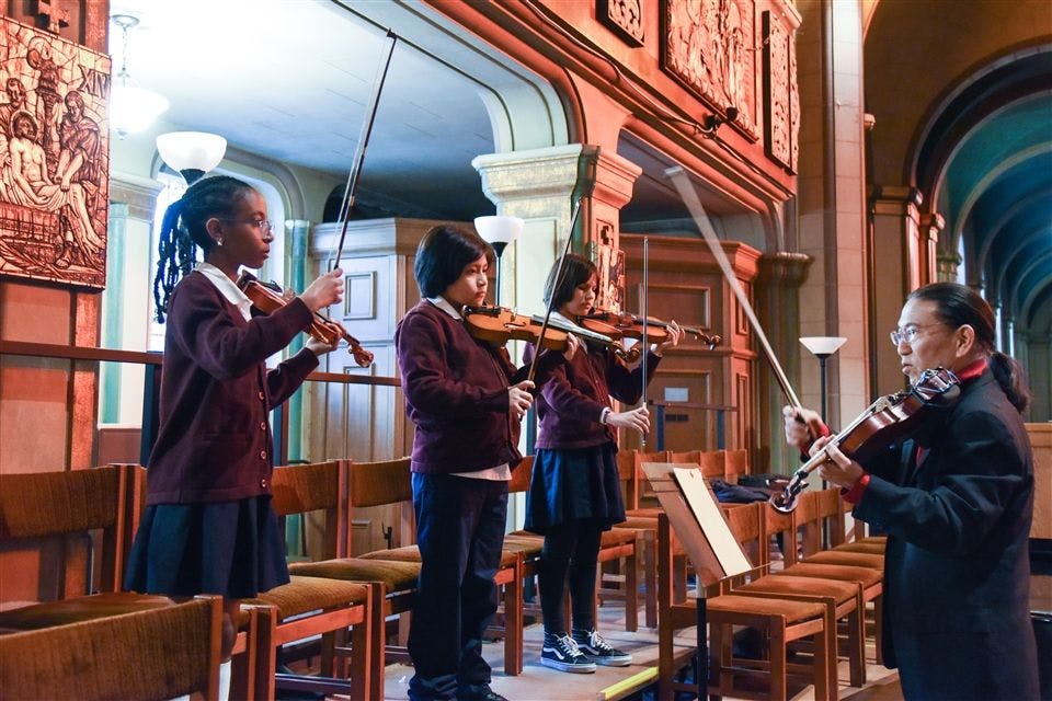 Children and a person playing violins