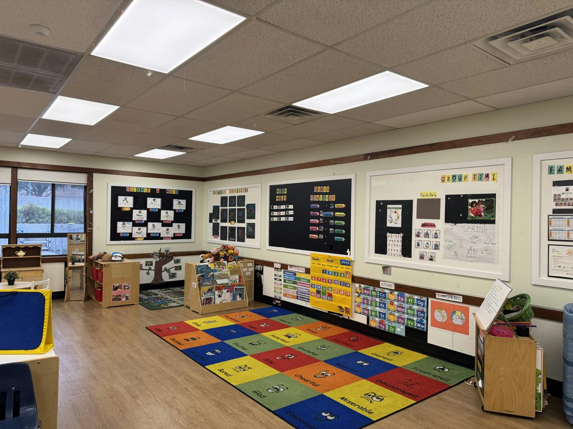 Colorful classroom with a large rug, educational posters, and activity centers