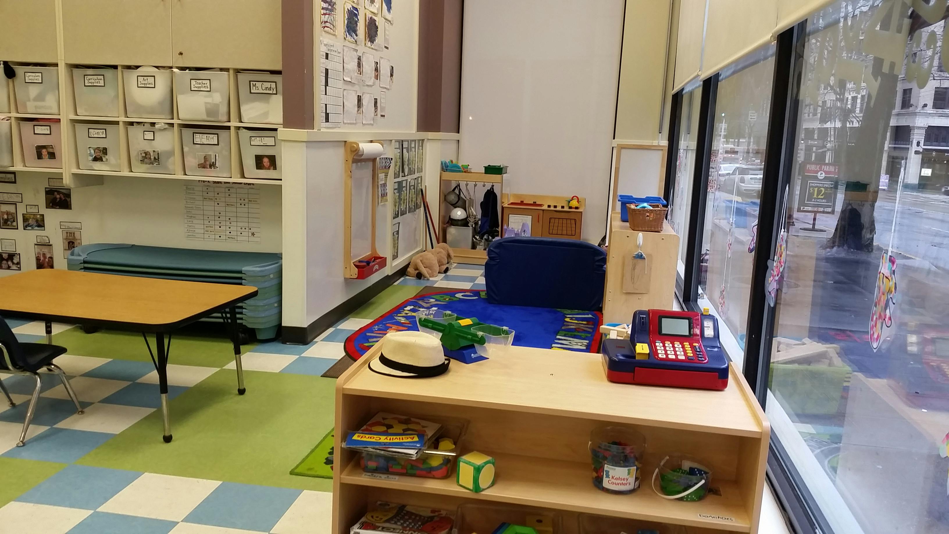 Classroom interior with tables, shelves, and a window overlooking a street