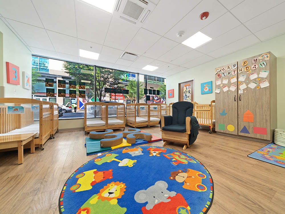 A classroom with cribs and a large window looking out onto a street