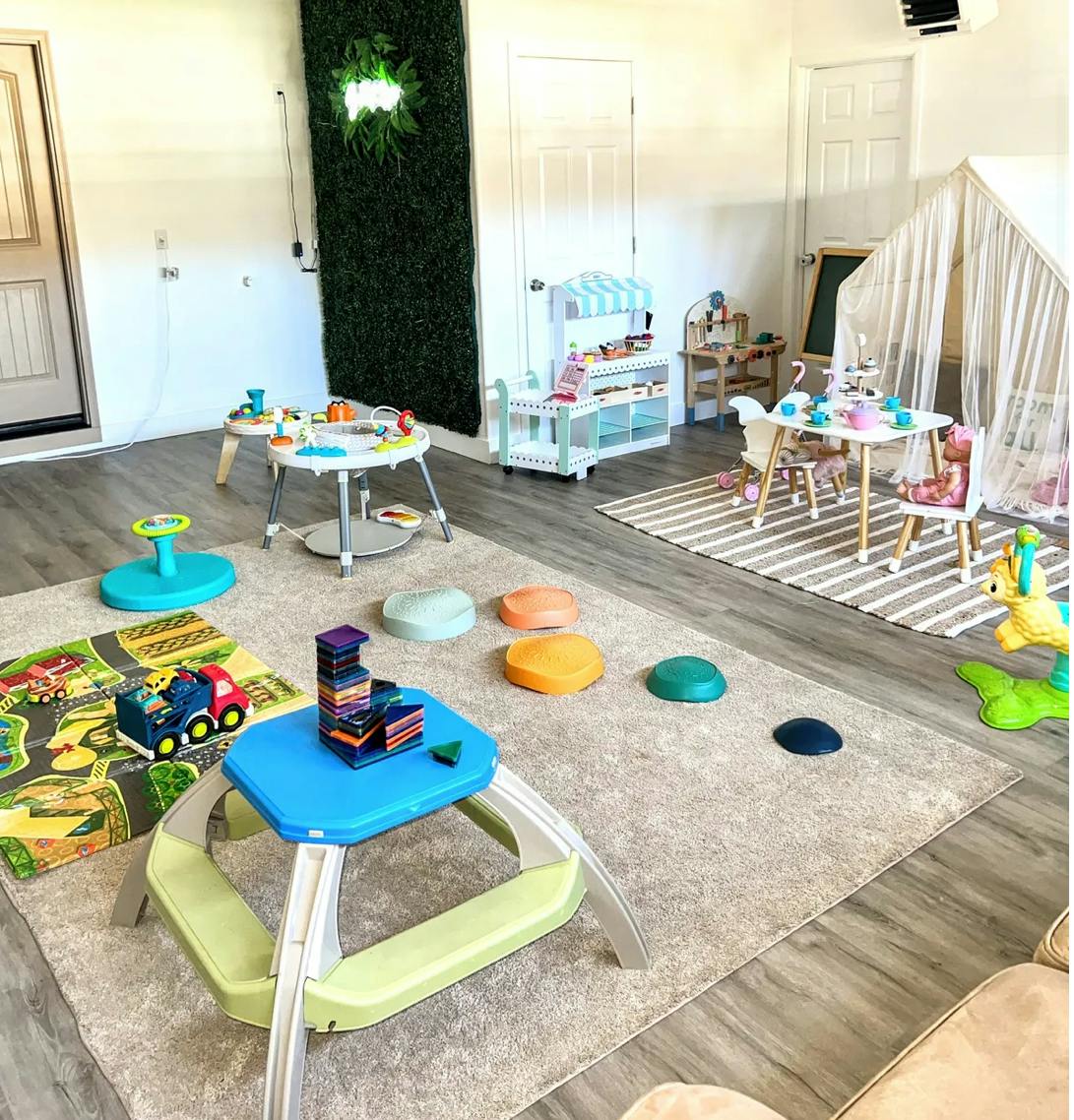 Indoor play area with various toys, tables, and a tent