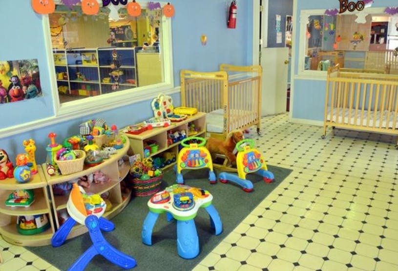 Nursery room with cribs, shelves of toys, and play equipment