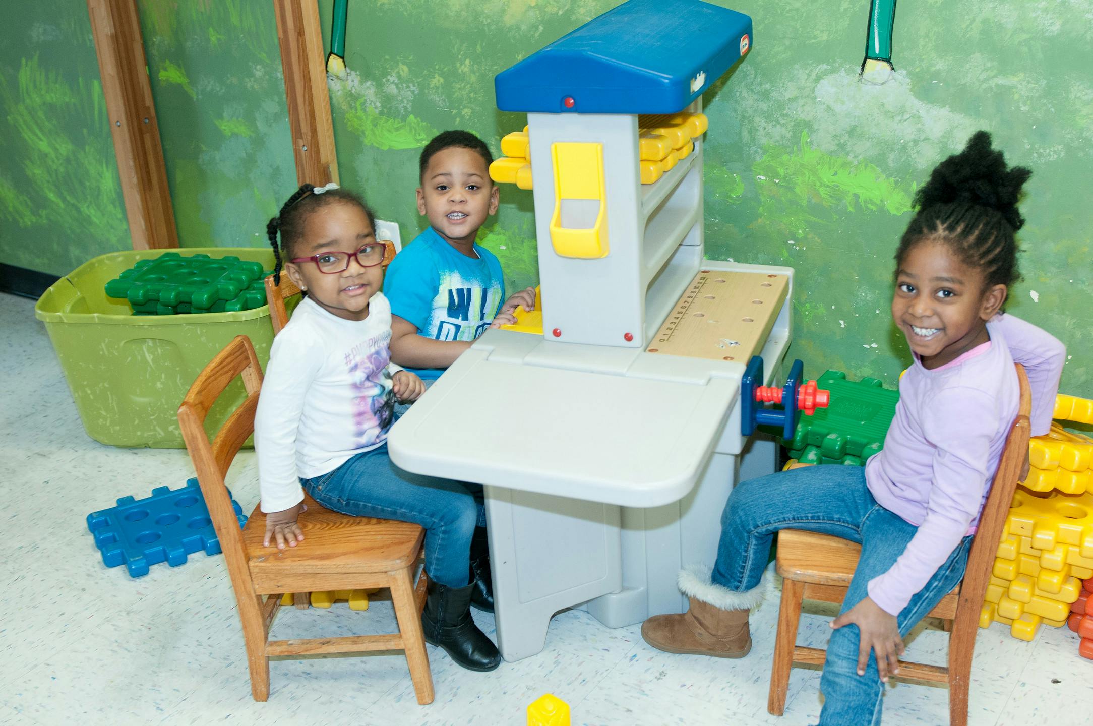 Three children playing with a toy kitchen set