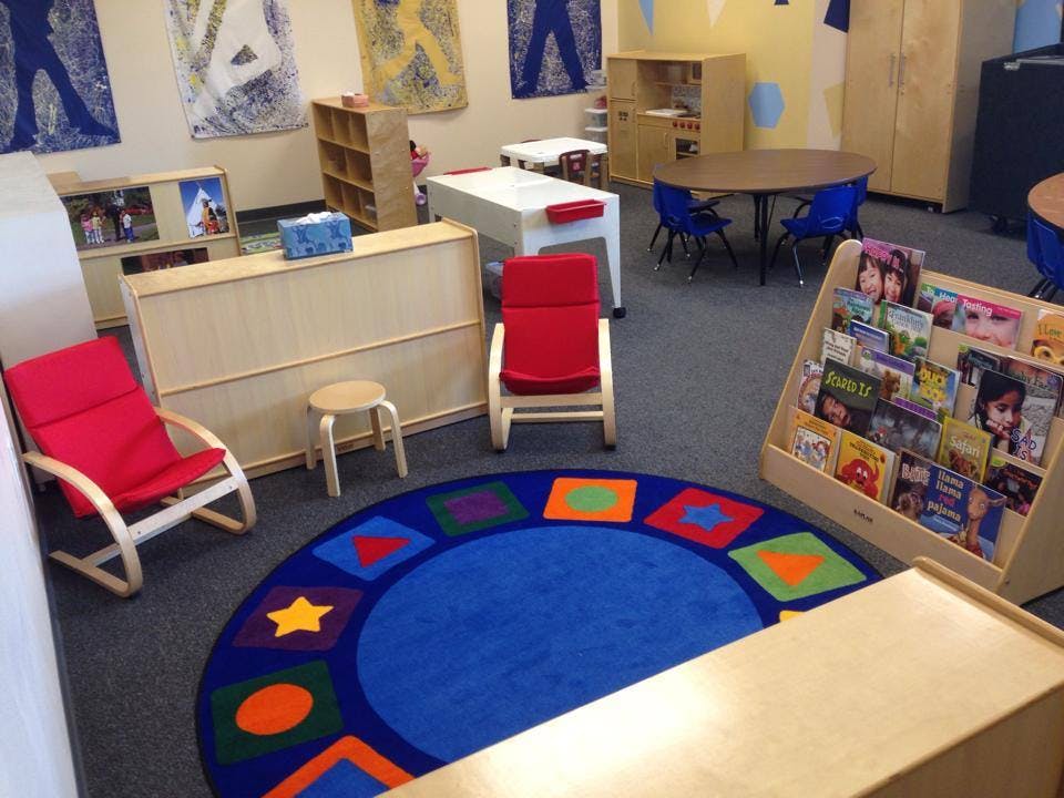 Classroom with a blue rug, red chairs, and bookshelves