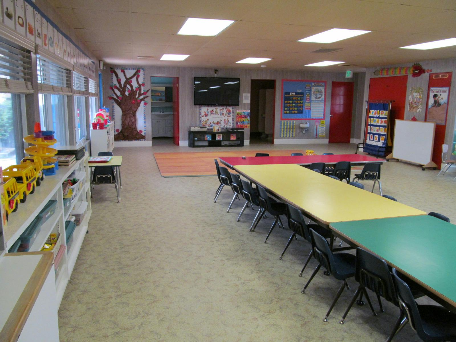 Classroom with long tables and chairs, shelves, and wall decorations