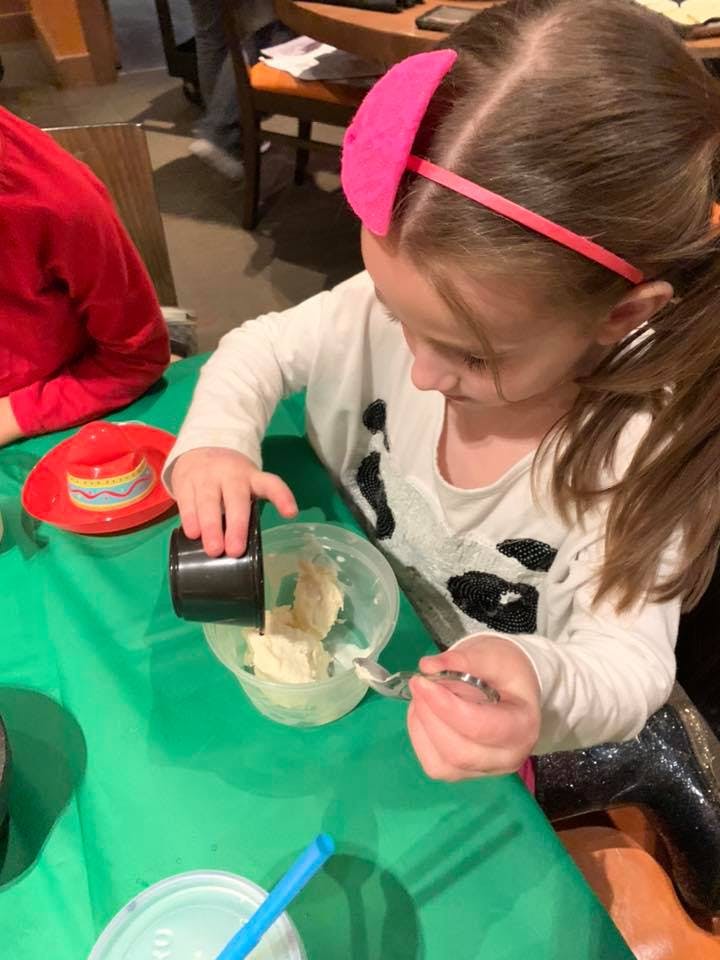 Child pouring from a measuring cup into a bowl