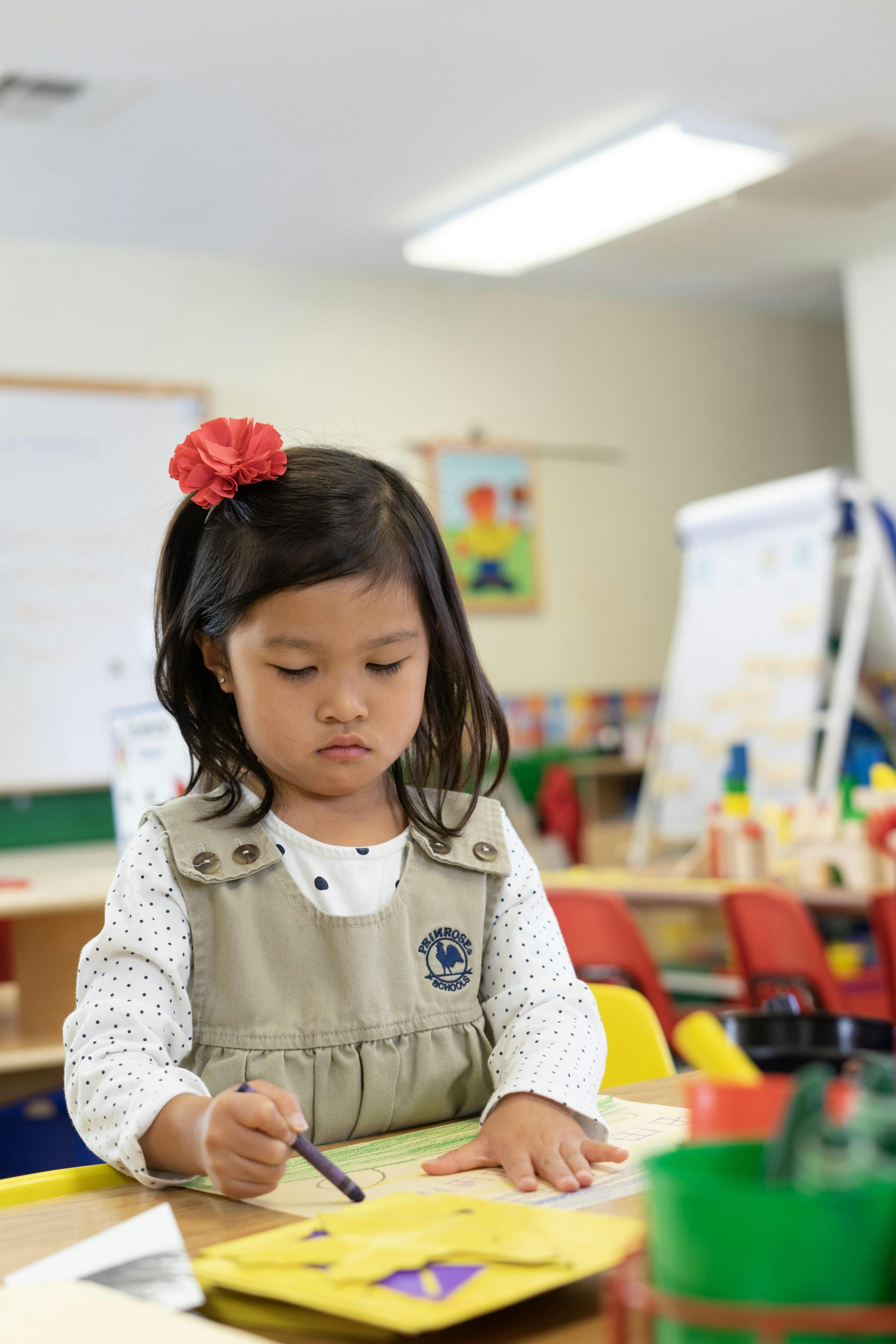 Child drawing with a crayon in a classroom