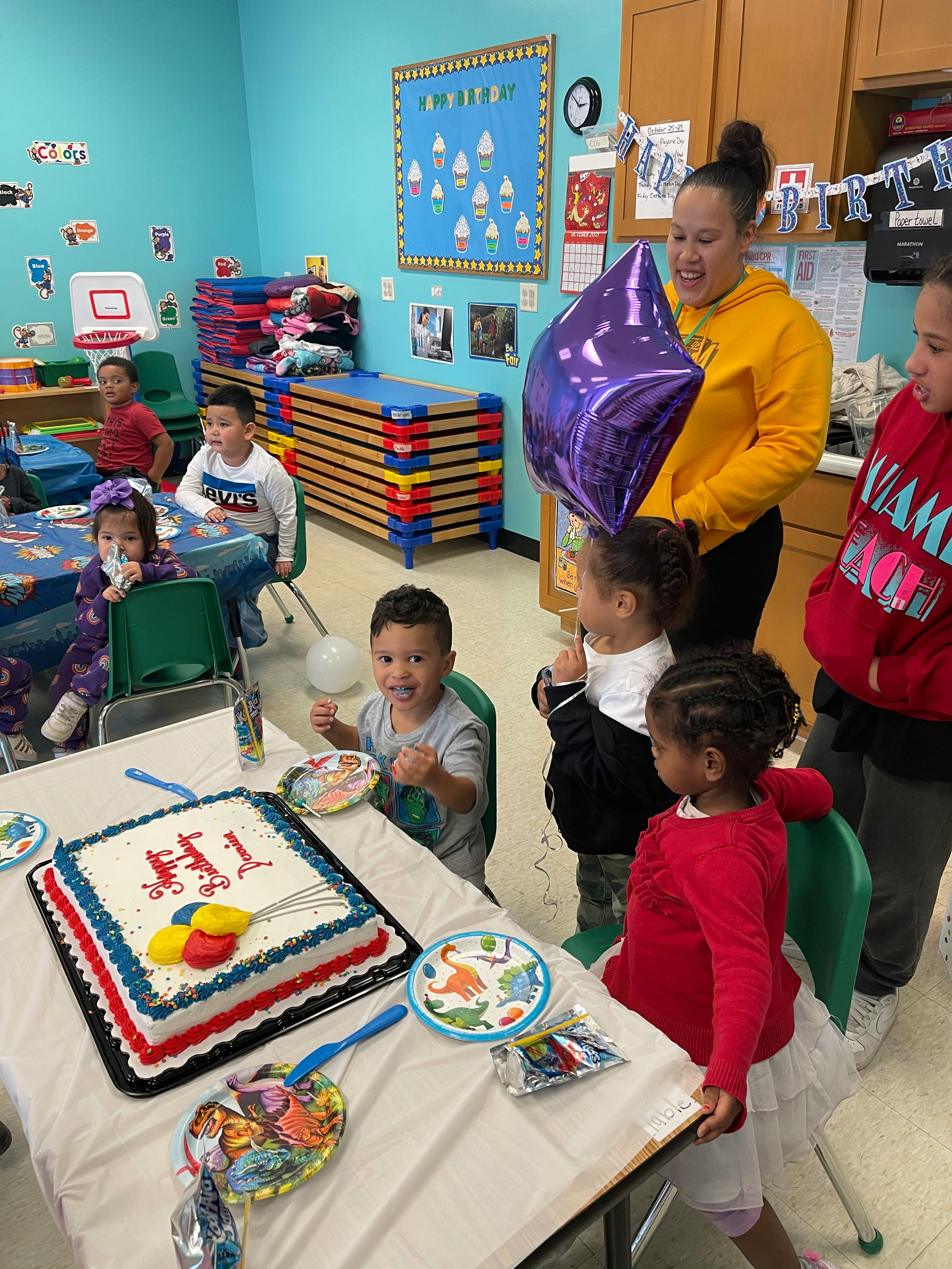 Adult and children gathered around a table with a birthday cake