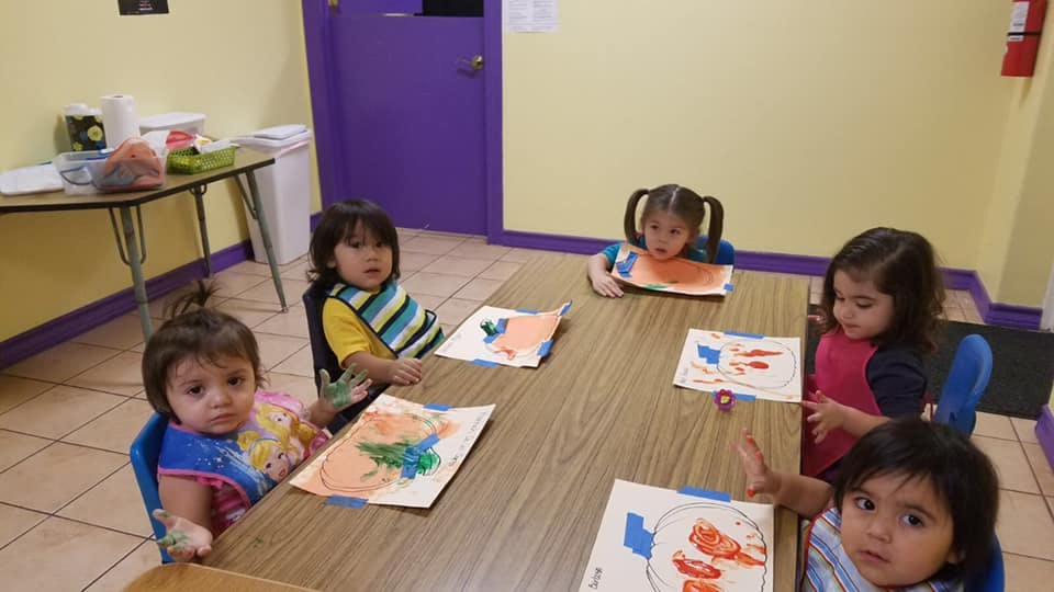 Children sitting at a table with drawings