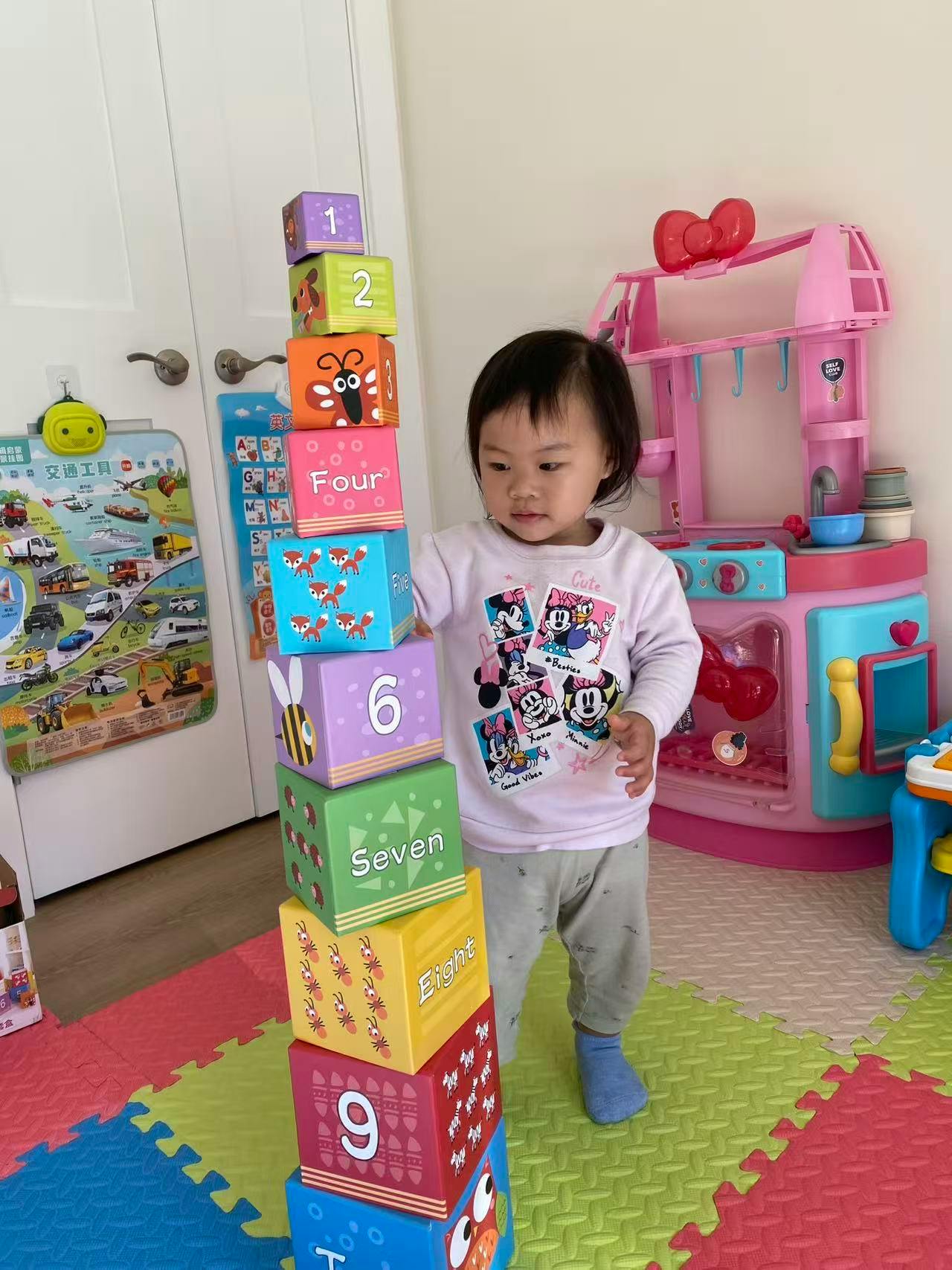 Child standing next to a tall stack of colorful number blocks