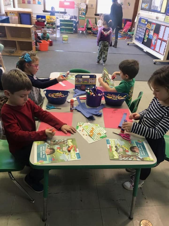 Children sitting at a table doing crafts in-class activities