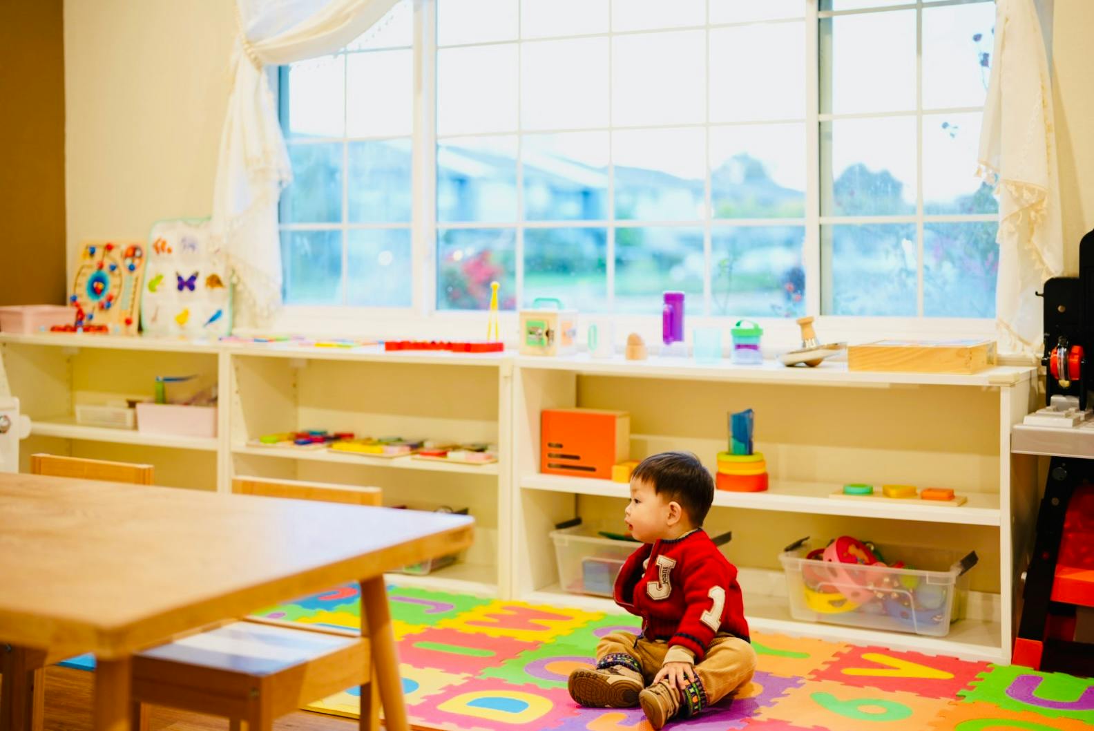 Child sitting on a colorful mat in a classroom