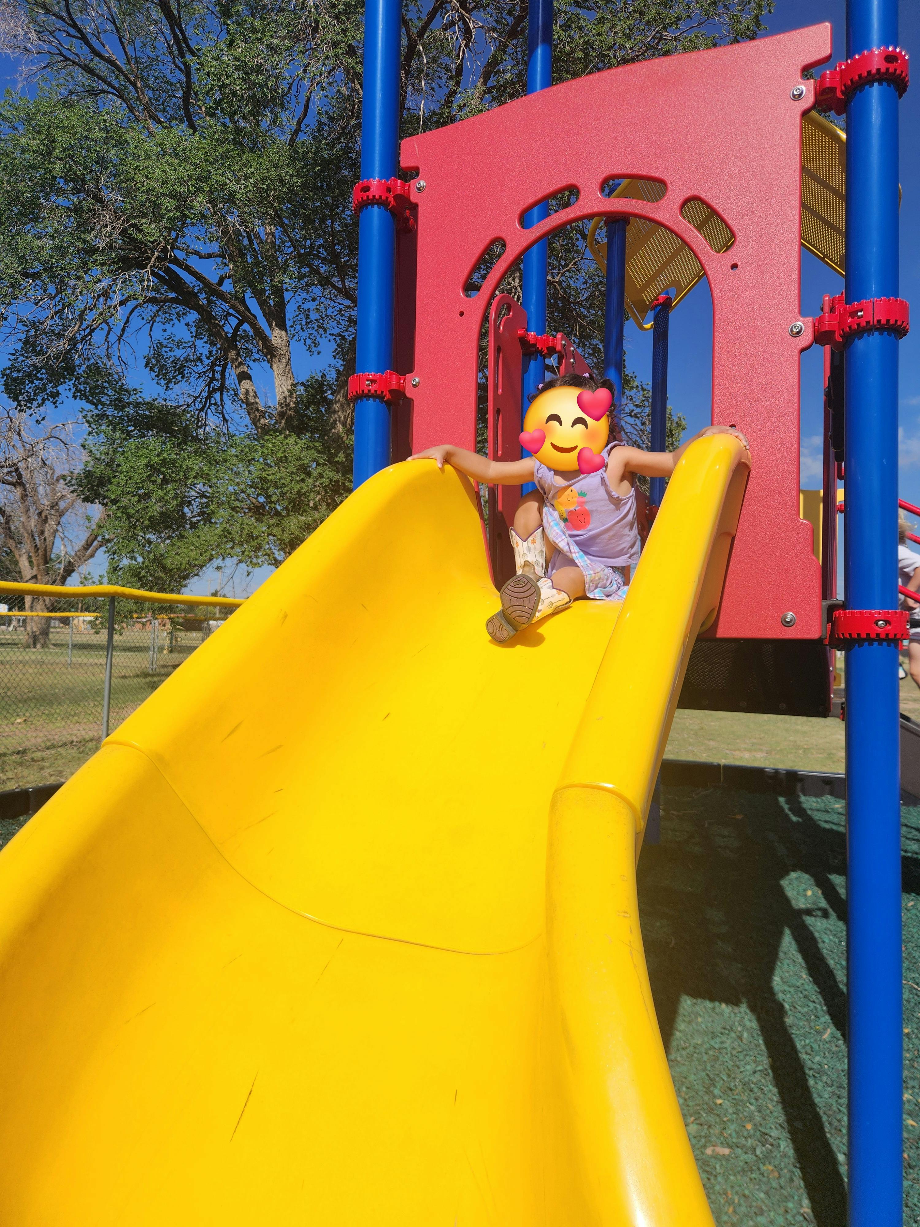 Child sitting on a yellow playground slide