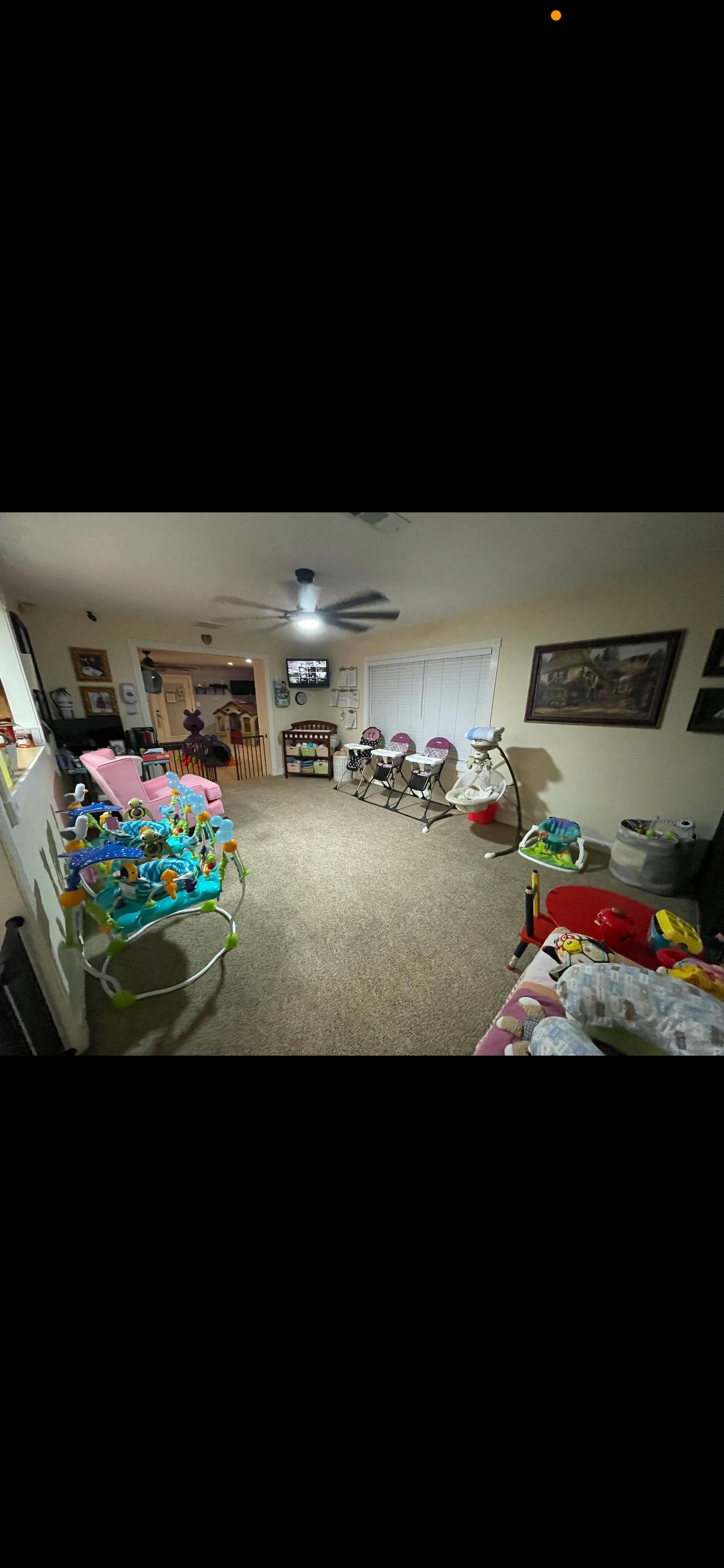Room with baby play equipment, high chairs, and a ceiling fan