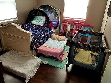 Child's bedroom with a bed, floor mattress, and playpen