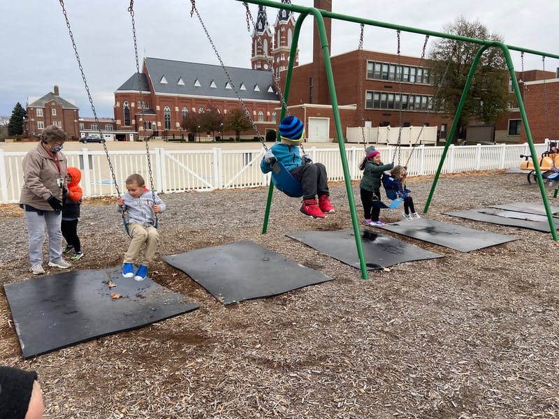 Adult and children on swings at a playground