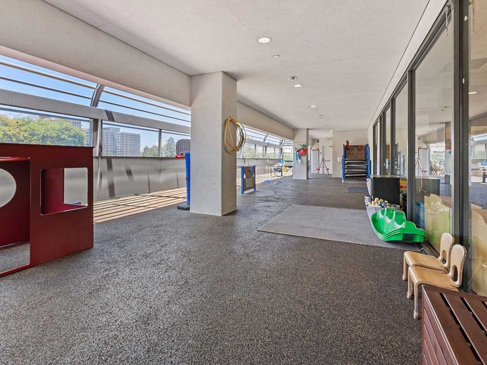Indoor play area with a red play structure and green ride-on toy