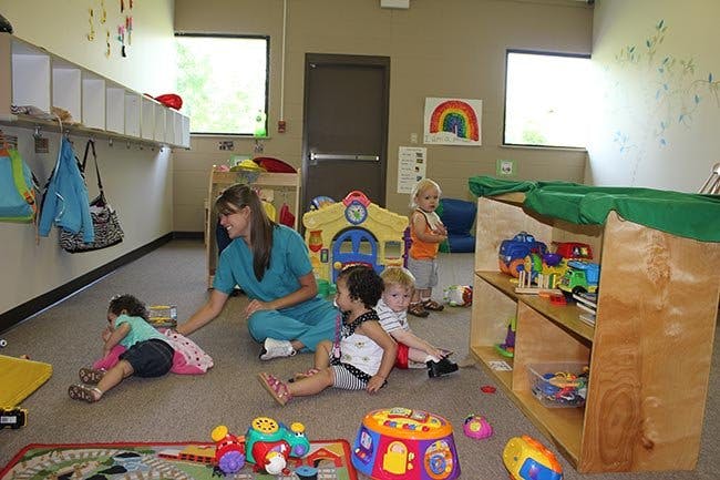Adult and children playing on the floor in a room with toys