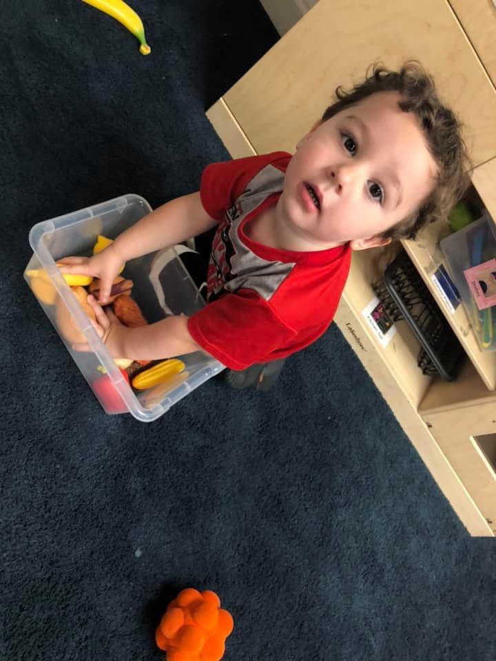 Child playing with toys in a clear container