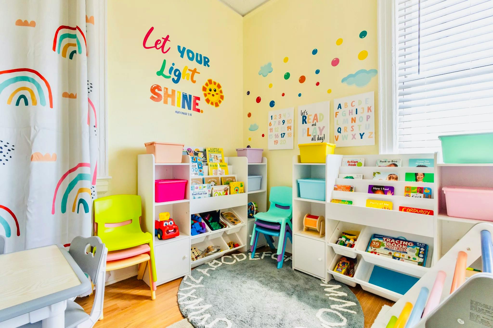 Colorful playroom with bookshelves, children's chairs, and wall decals with text