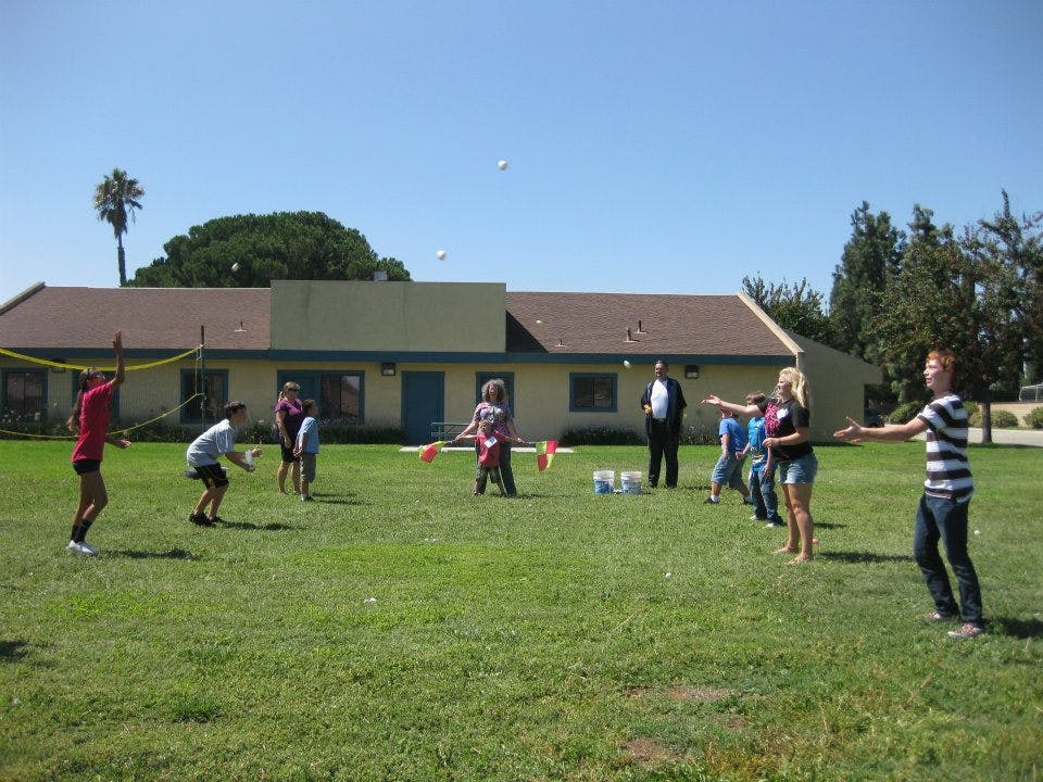 People playing a game with balls and rackets on a grassy field