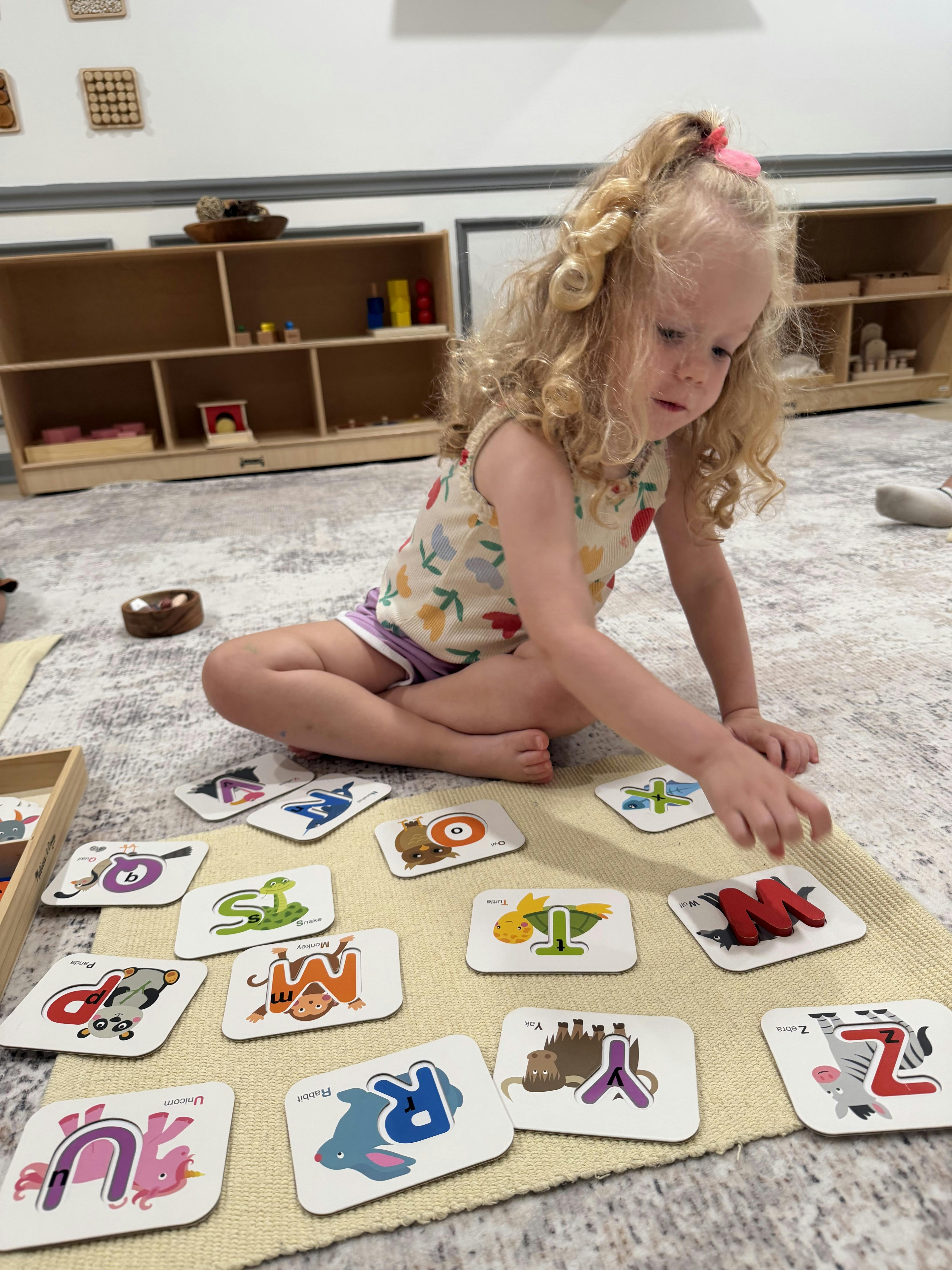 Child playing with alphabet letter cards on a mat