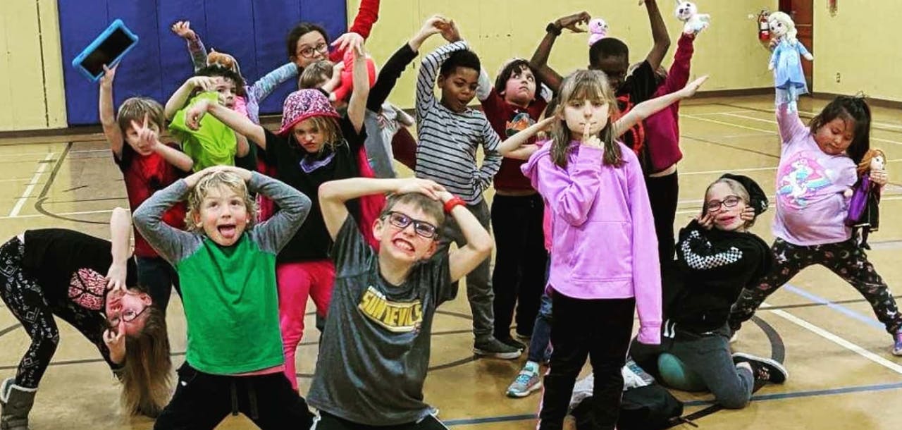Group of children posing with arms raised in a gym