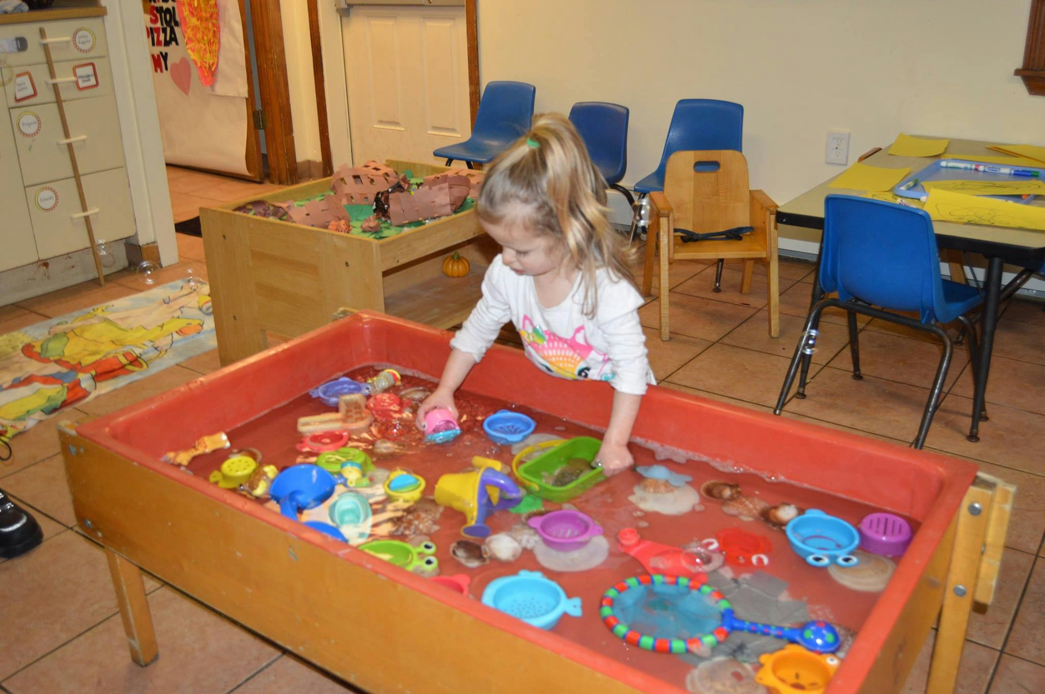Child playing in a sand and water table with toys