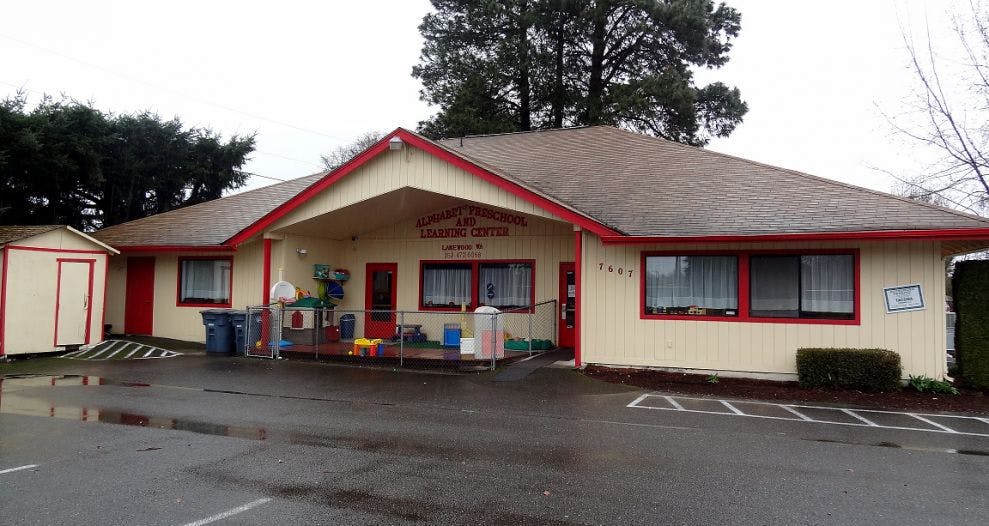 Single-story building with light-colored siding and red trim